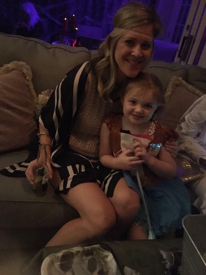 An adult guest and a small child seated together on a couch in costume at The Witch House in 2018