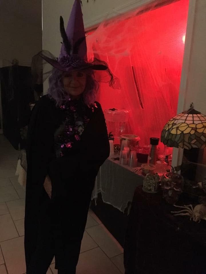 A guest in a tall witch hat standing near a red-lit refreshment station at The Witch House in 2018