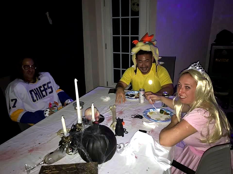 Costumed guests gathered around a candlelit dining table at The Haunted Tavern in 2019