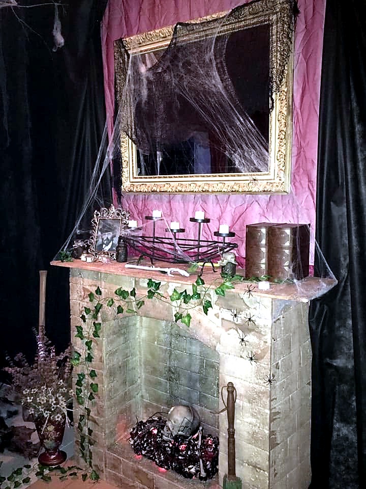 A cobwebbed fireplace decorated with skulls and candles at The Haunted Tavern in 2019