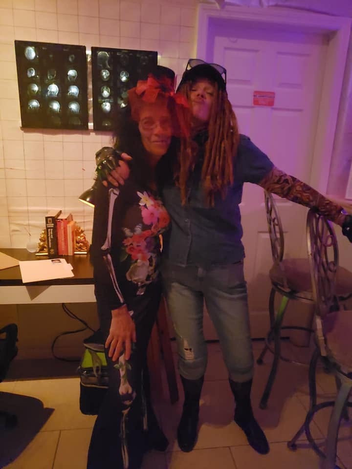 Two costumed guests posing together beside illuminated x-ray-style displays at the 2020 Halloween party
