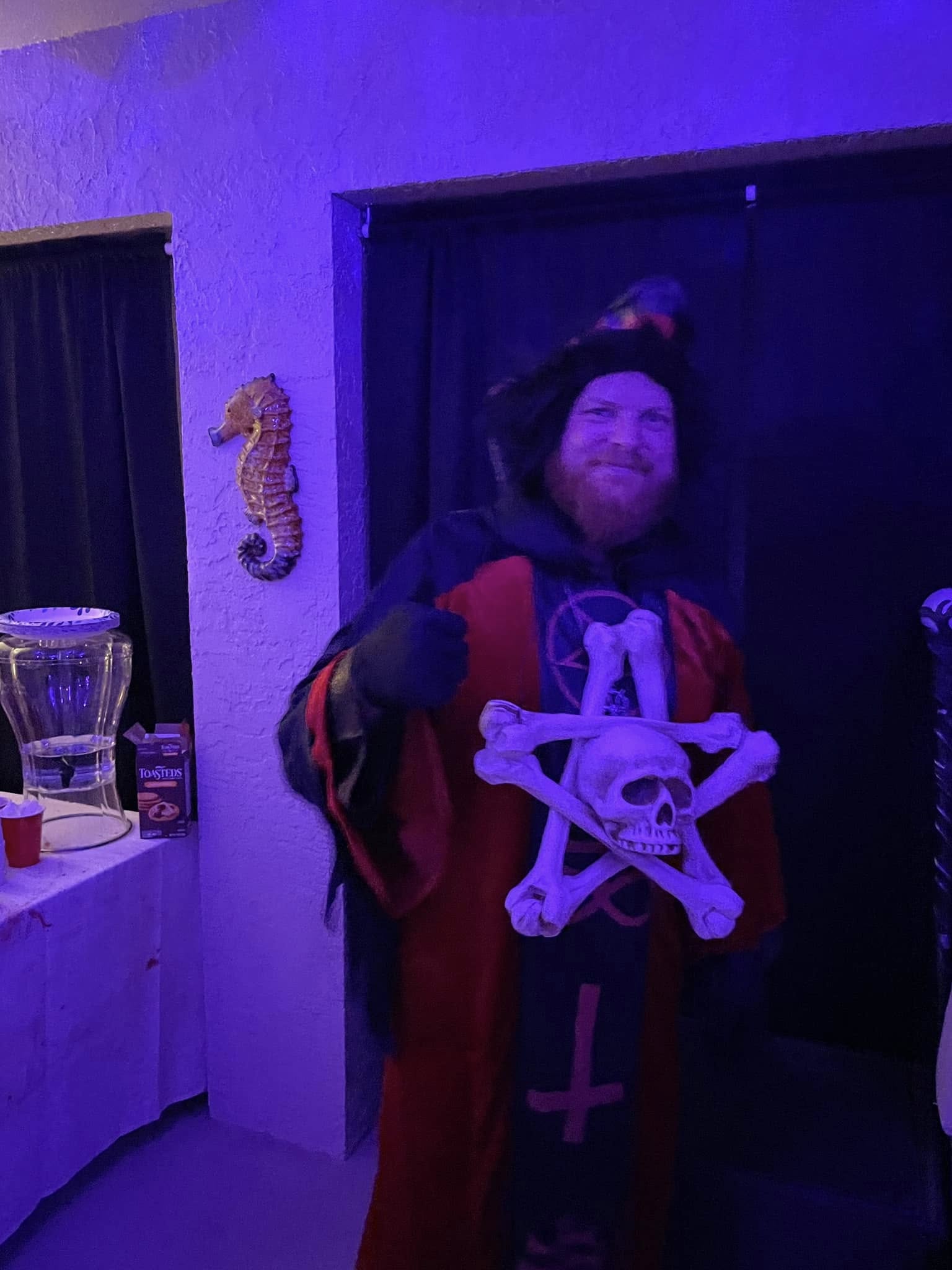 A horned guest in a red Hellfire robe giving a thumbs up at the 2023 party
