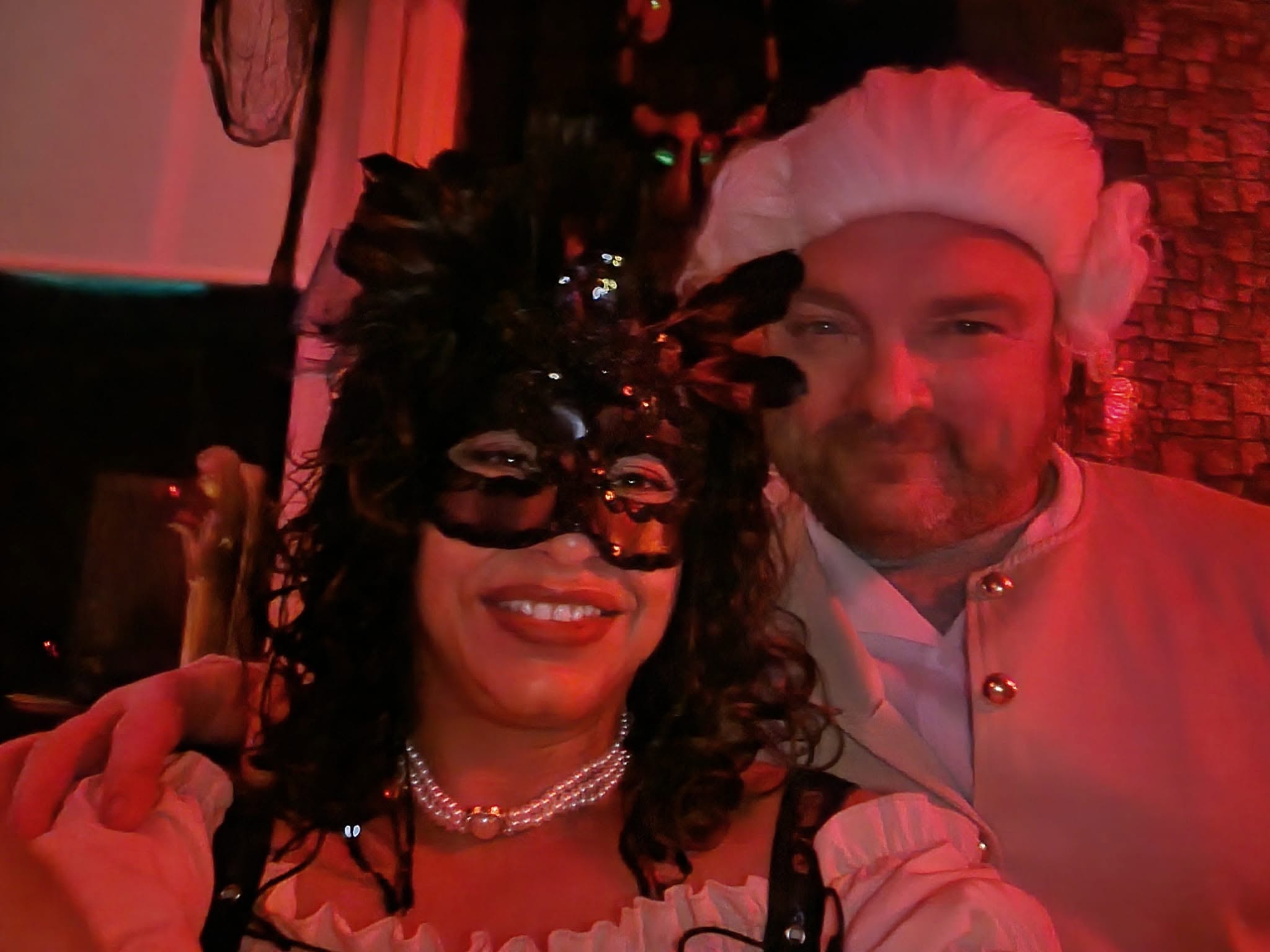Two guests in masked and period-inspired attire posing together at the 2023 party
