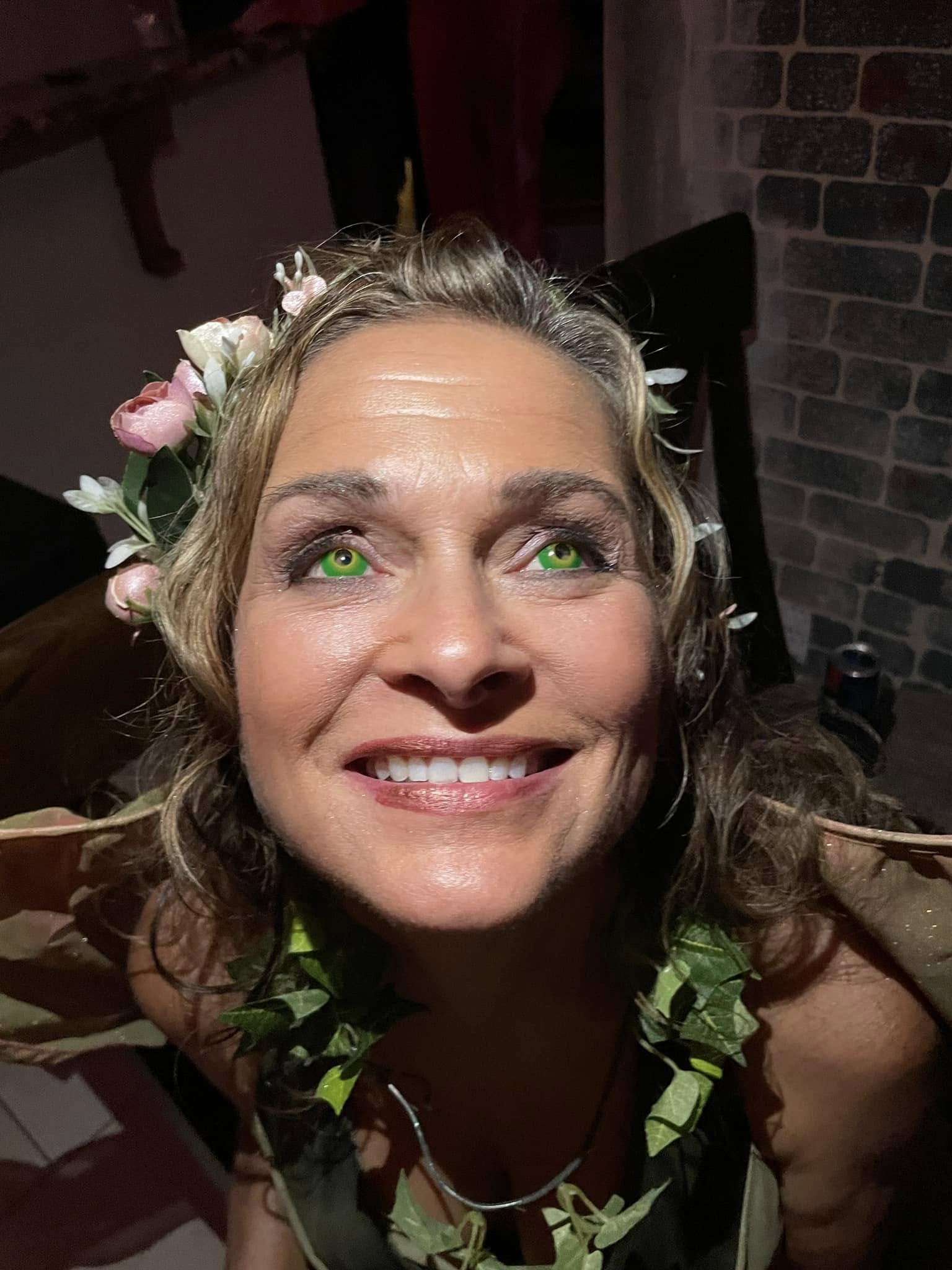 A close portrait of a guest with glowing green eyes and ivy details at the 2023 party