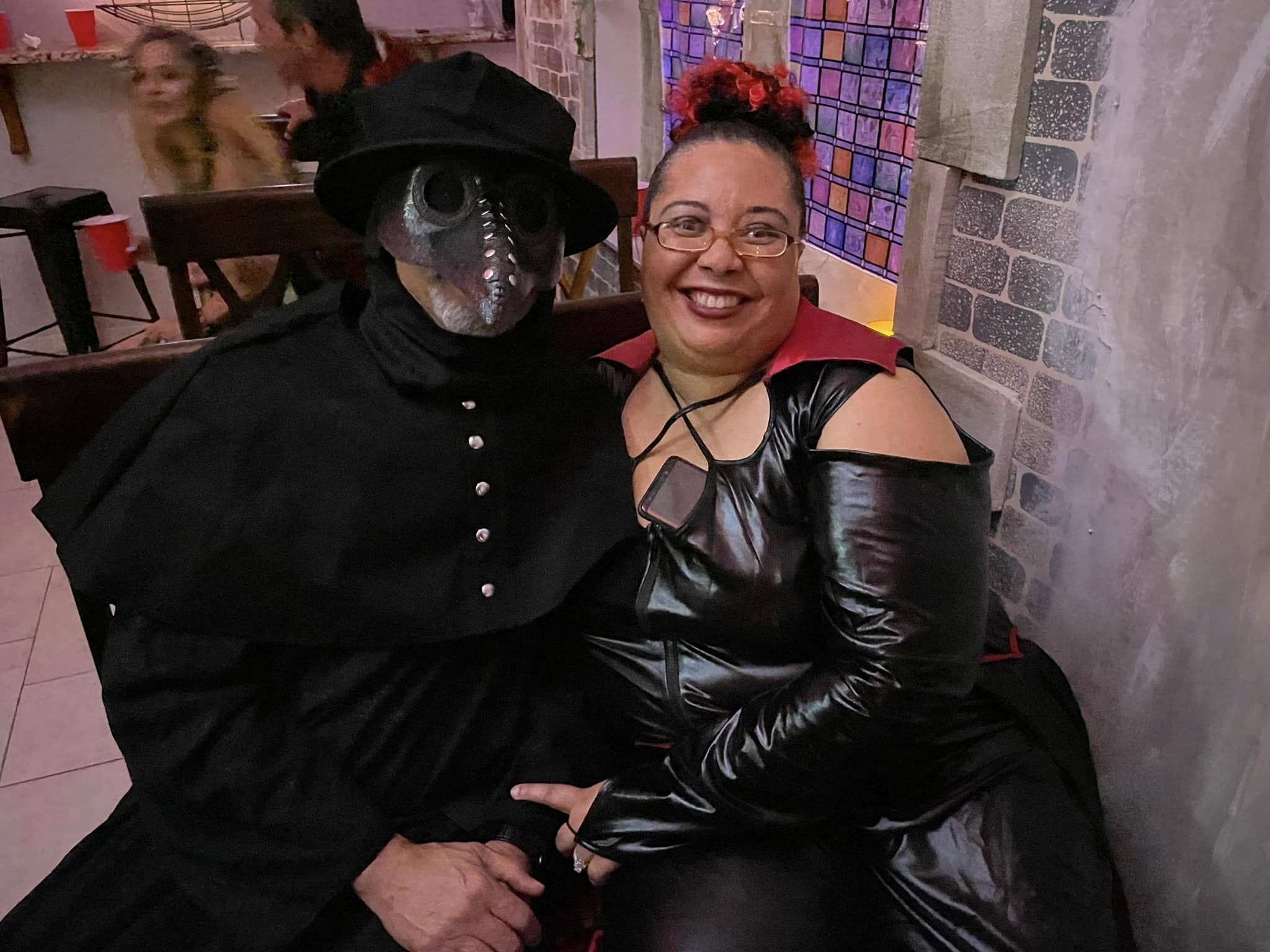 A seated couple in plague doctor and vampiric costumes at the 2023 party