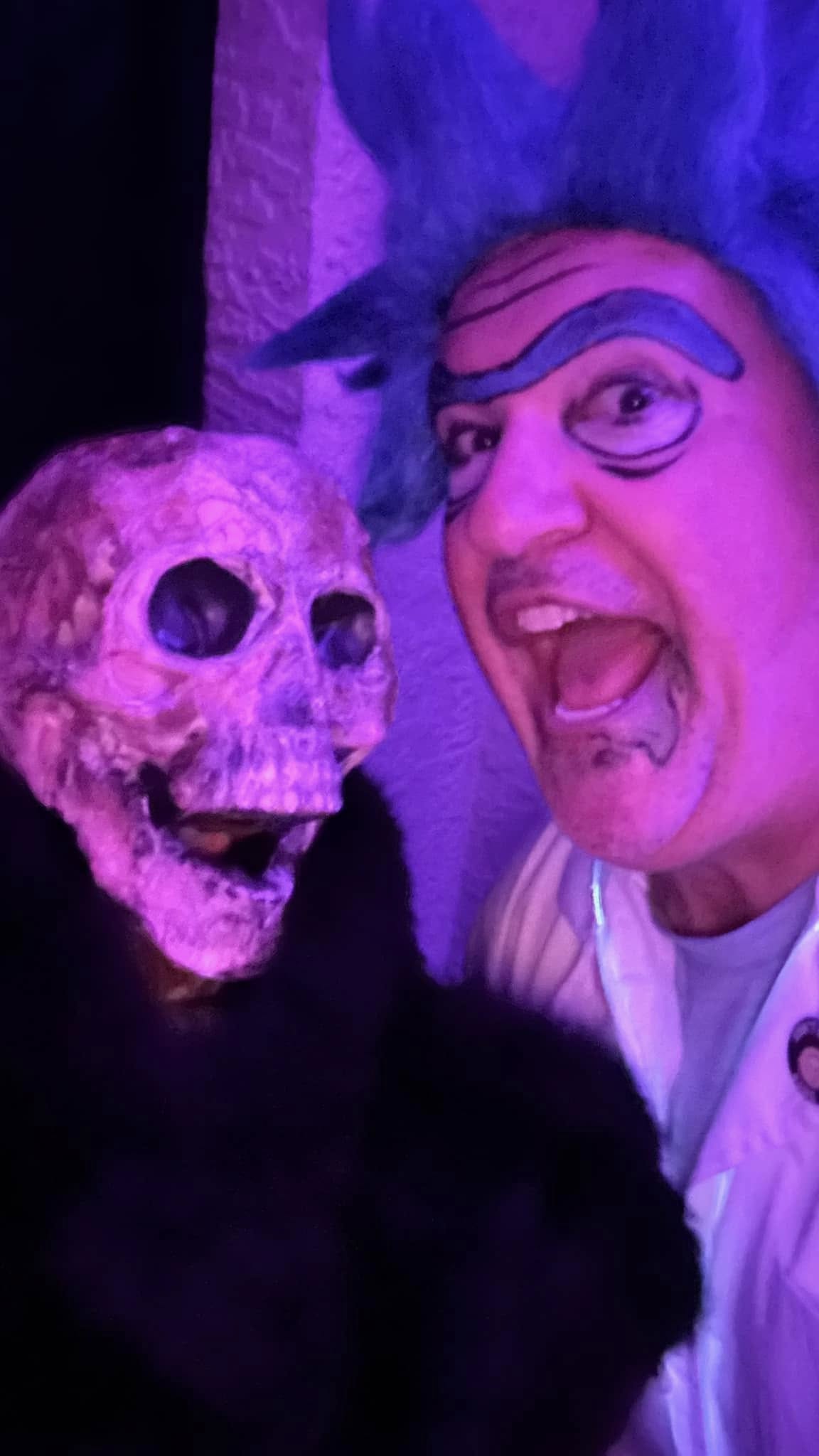 A guest posing playfully beside a skull figure under purple light at the 2024 party