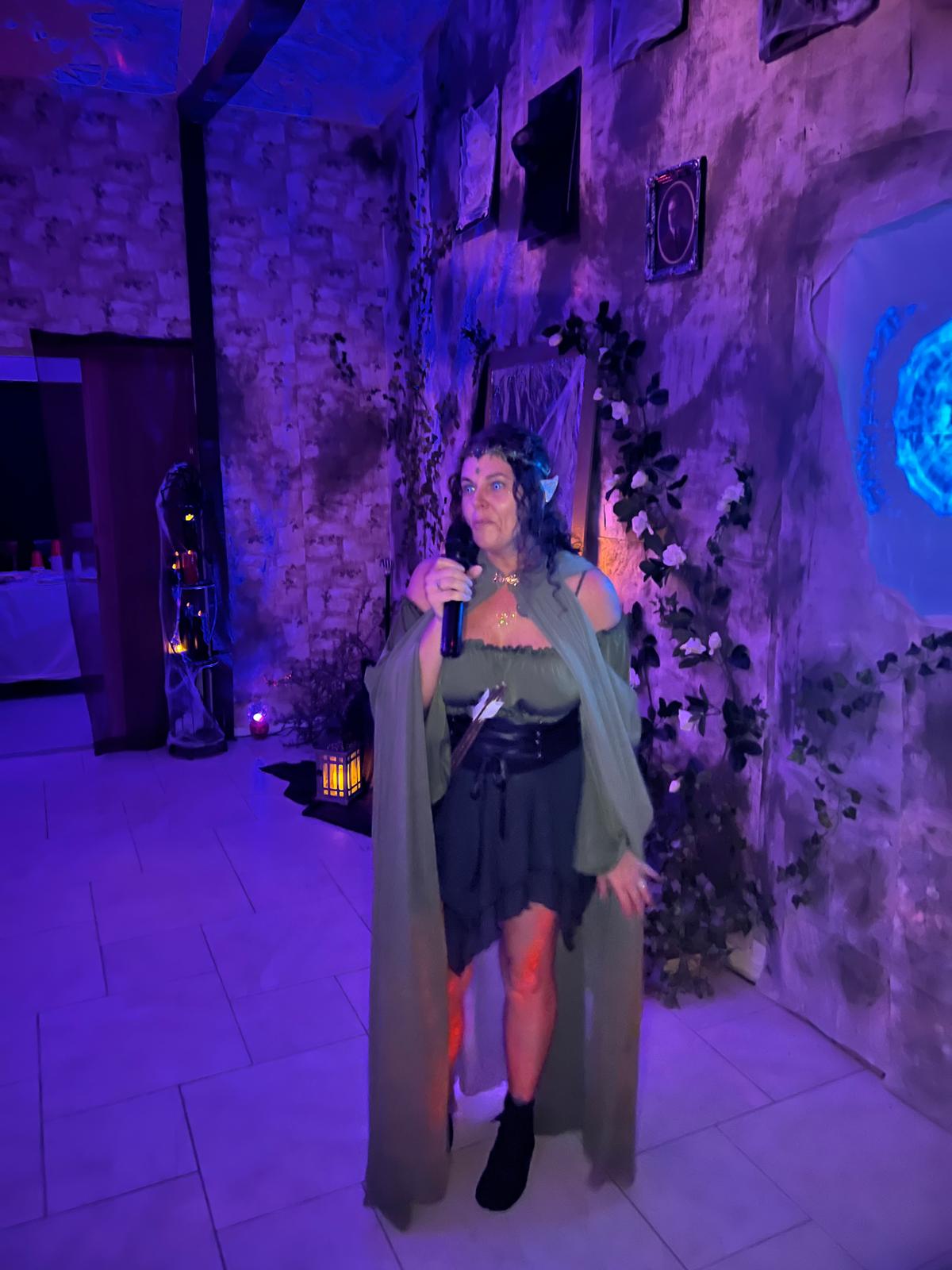 A guest in green attire addressing the room near the portal at the 2024 party