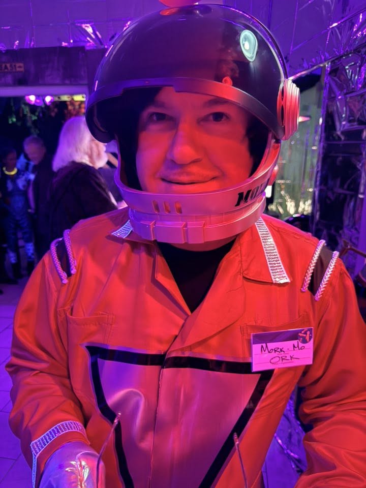 A close portrait of a guest in a bright red astronaut suit and oversized helmet at The Space Station in 2025