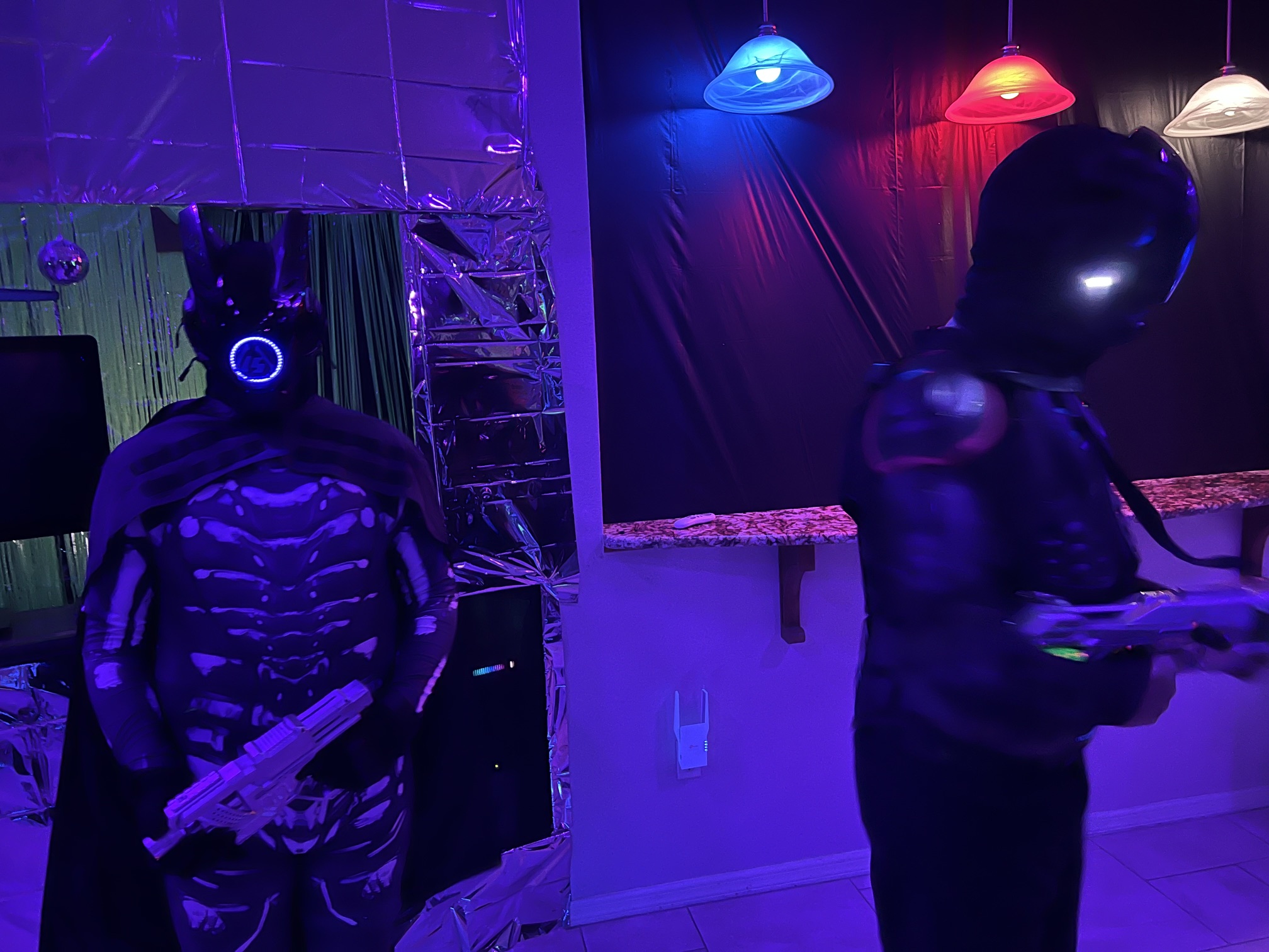 Two armored sci-fi figures standing watch beneath colored hanging lights at The Space Station in 2025
