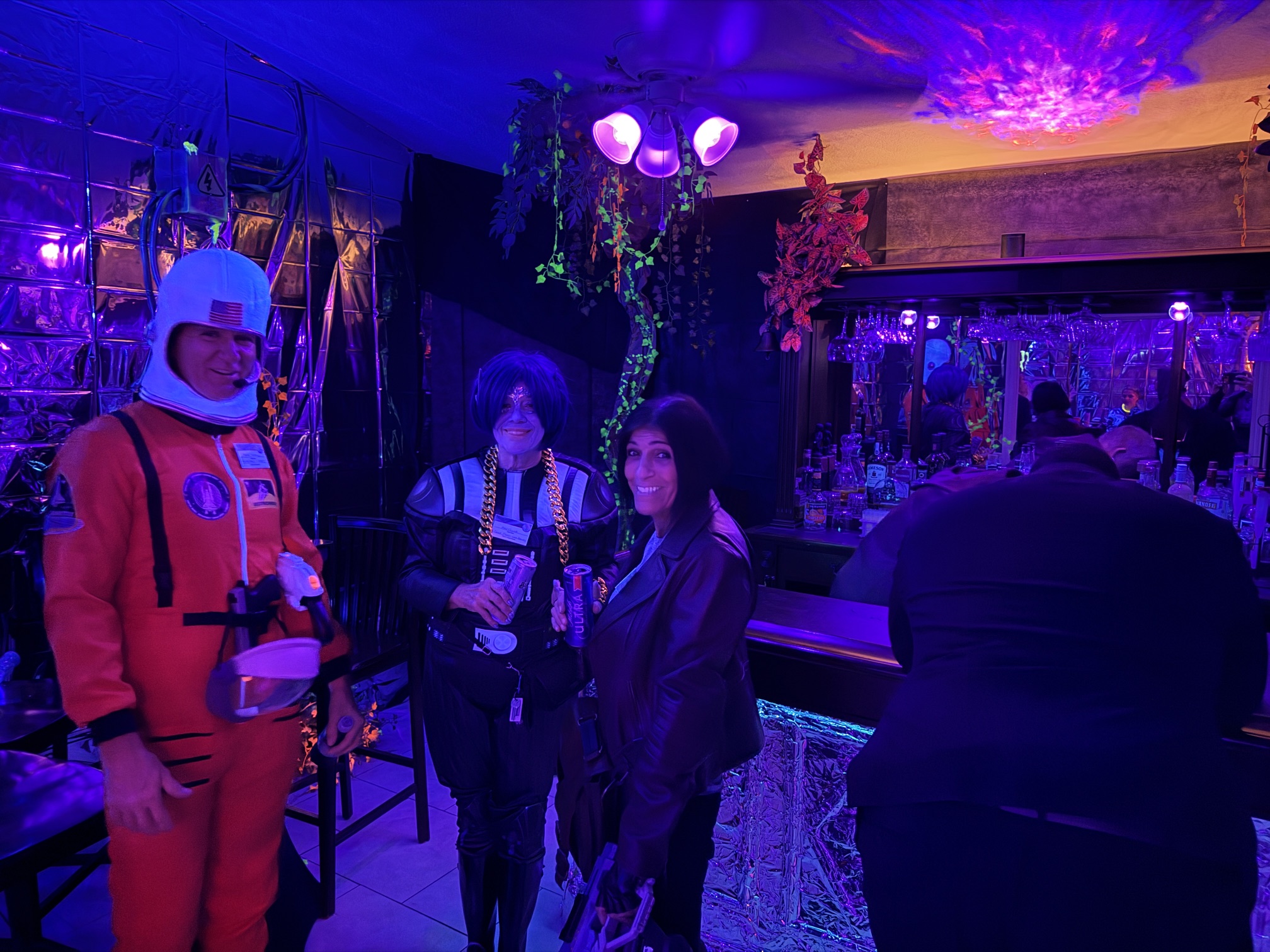 Guests in retro-futurist costumes gathered around the glowing station bar at The Space Station in 2025